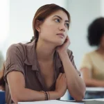 Young woman in classroom looking thoughtfully to the side